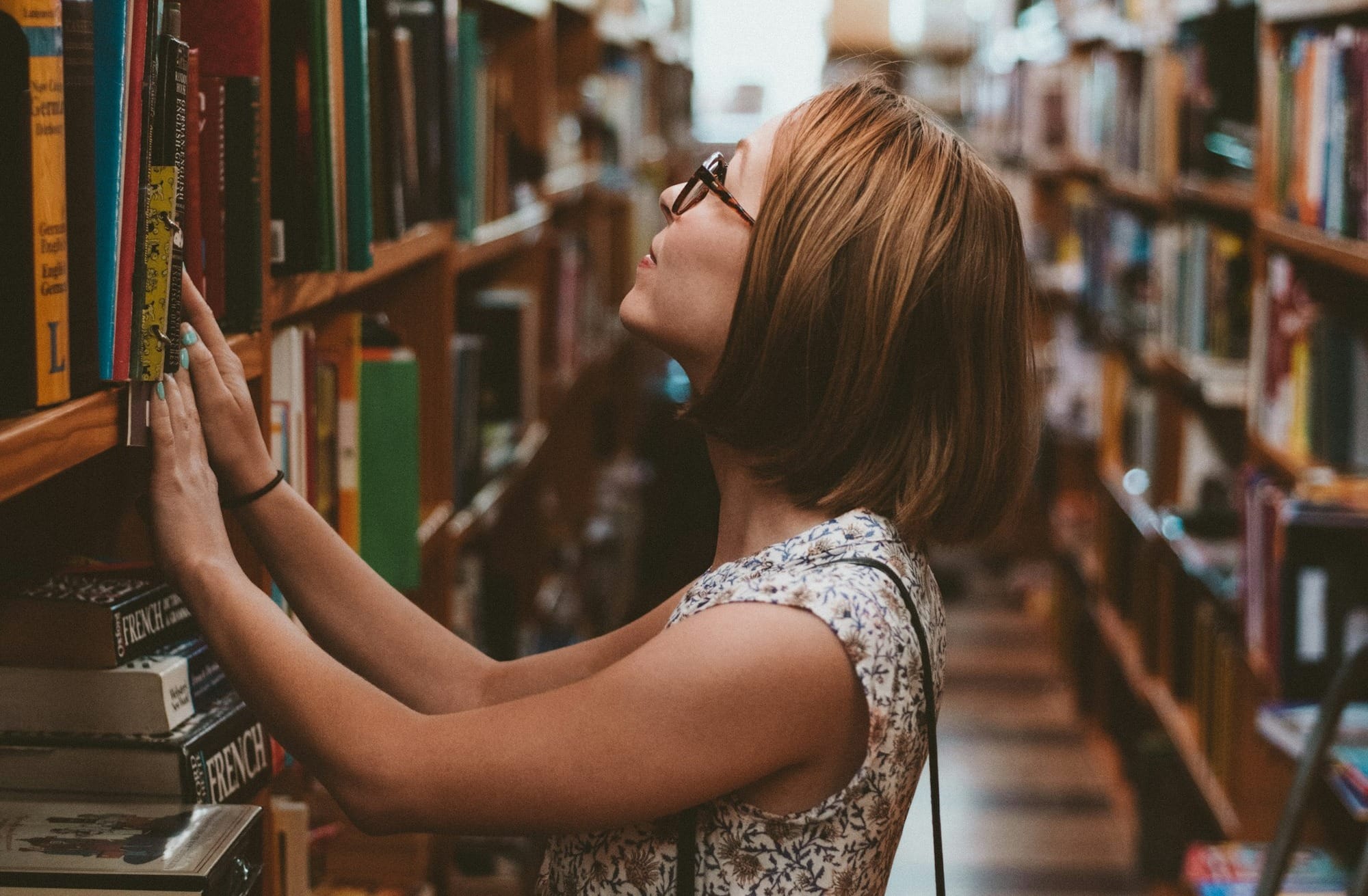 woman standing between library book shelves